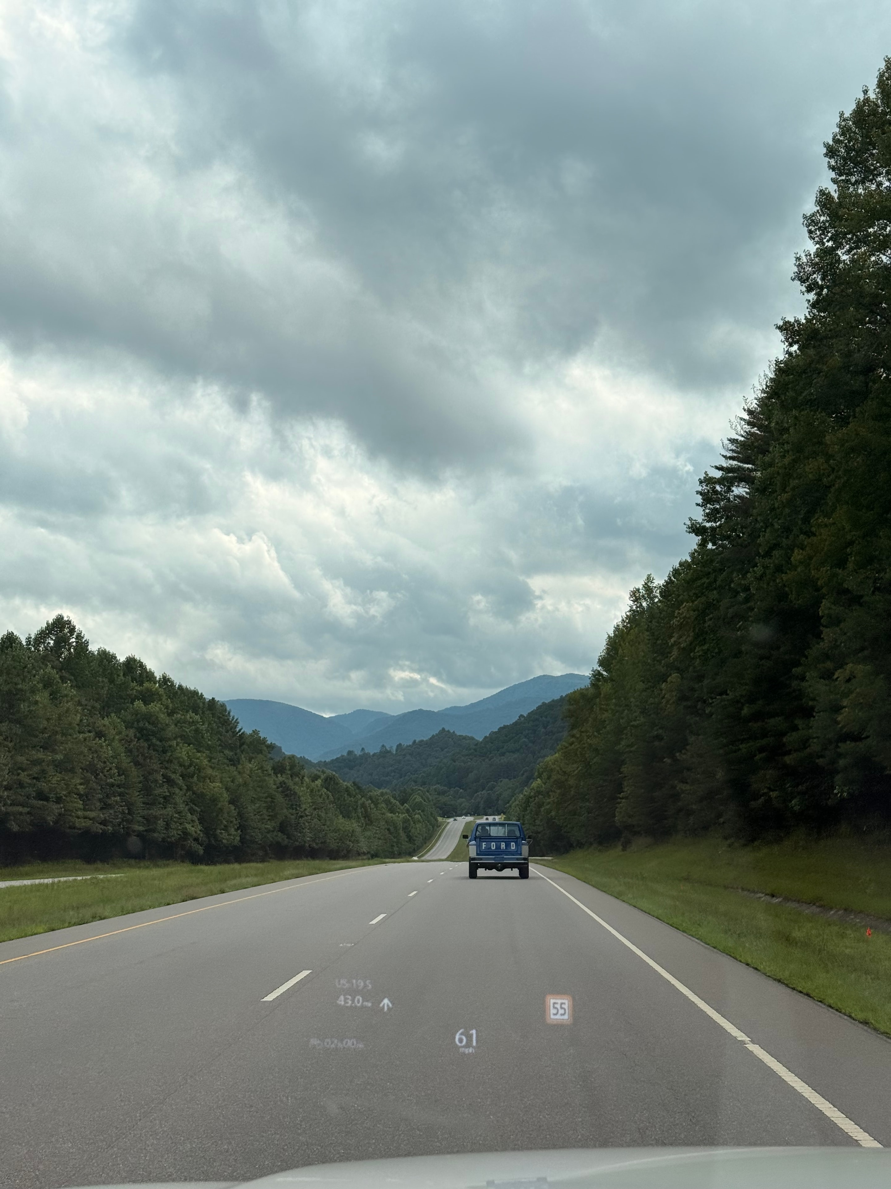Mountain highway with dramatic clouds and a Ford truck passing by