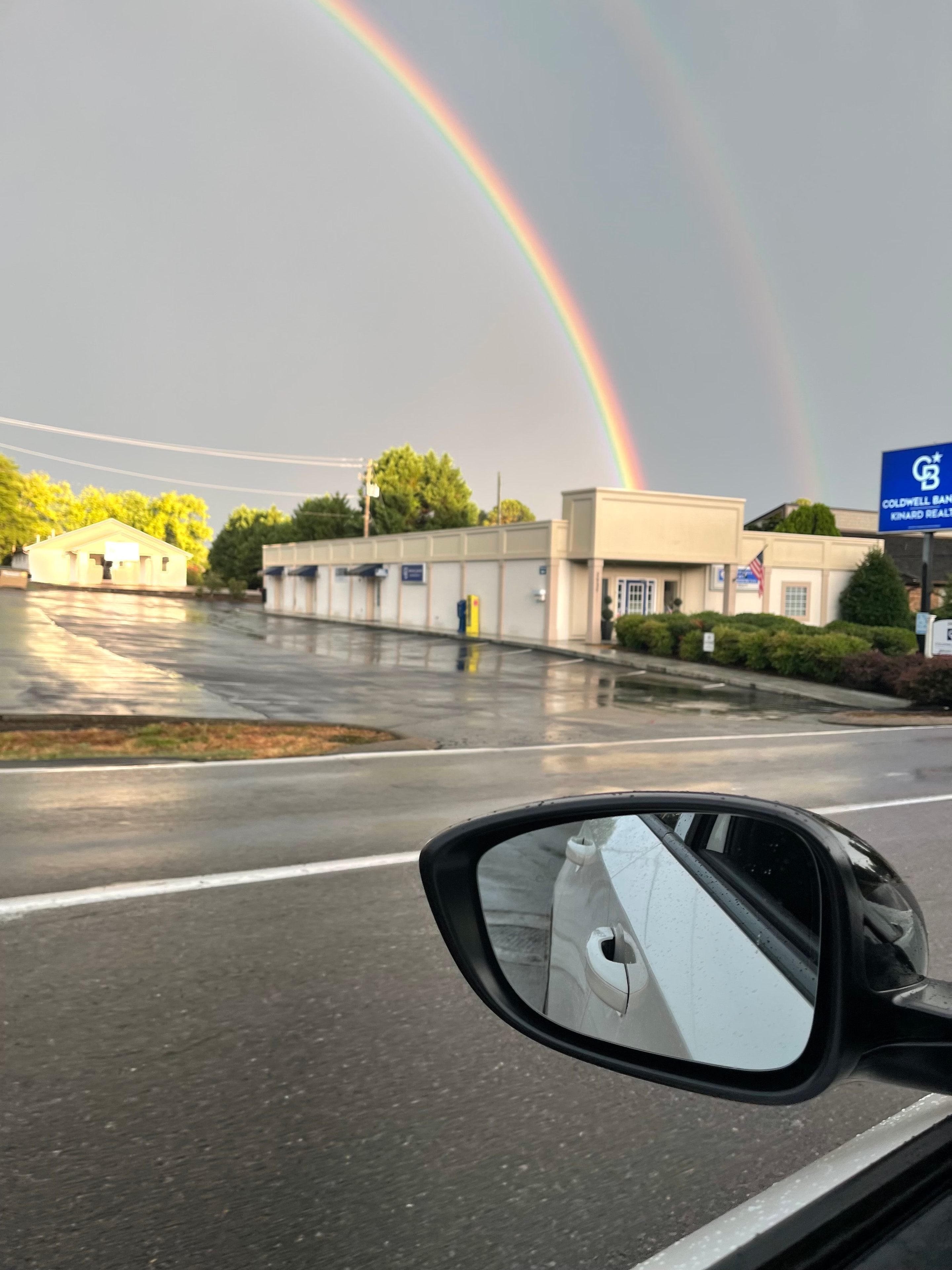 Rainbow arching over a street scene from a car window